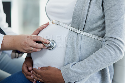 Buy stock photo Shot of an unrecognizable female doctor listening to movement inside of a pregnant patient with a stethoscope at a hospital during the day