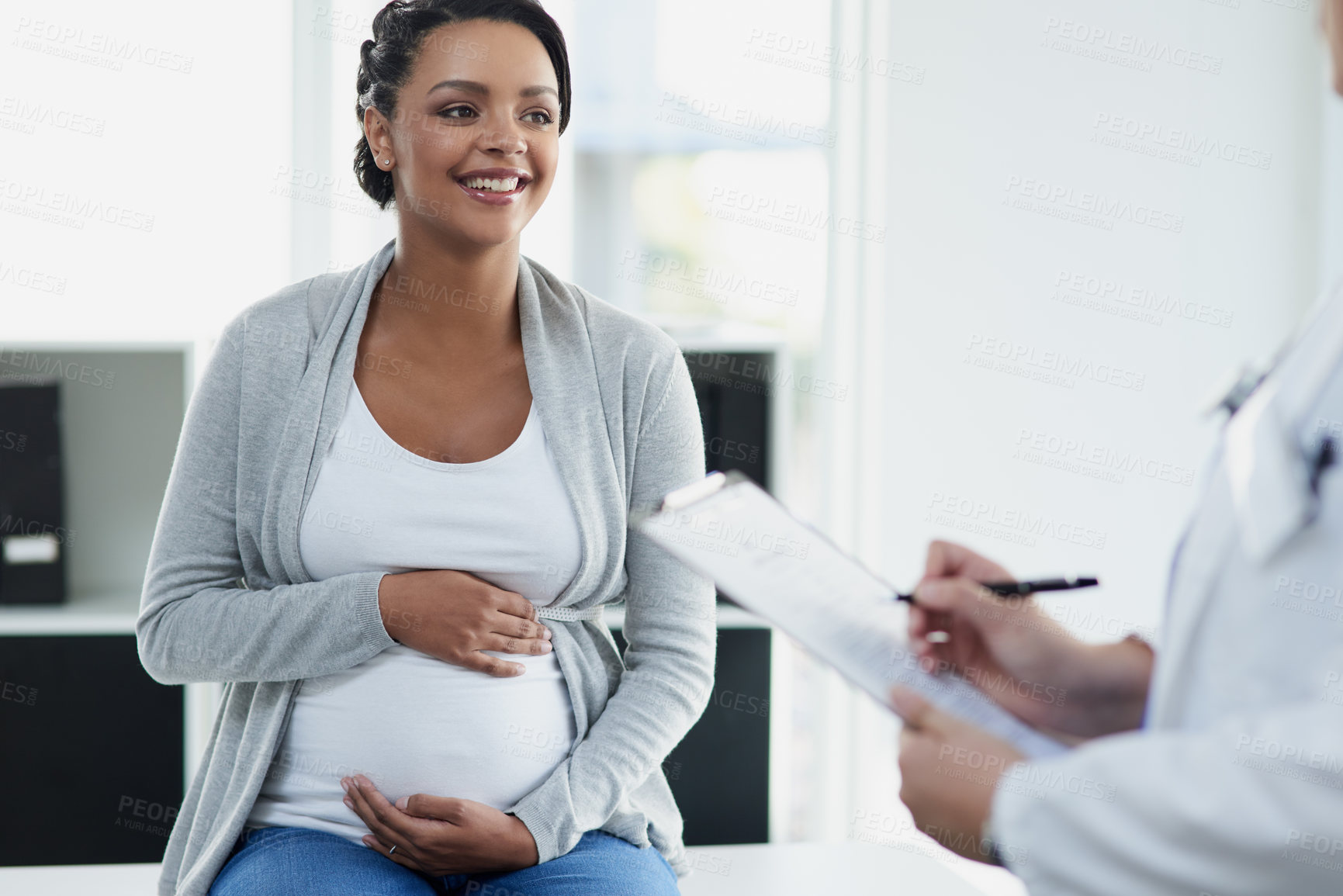 Buy stock photo Shot of a confident female doctor consulting with a pregnant patient at a hospital during the day
