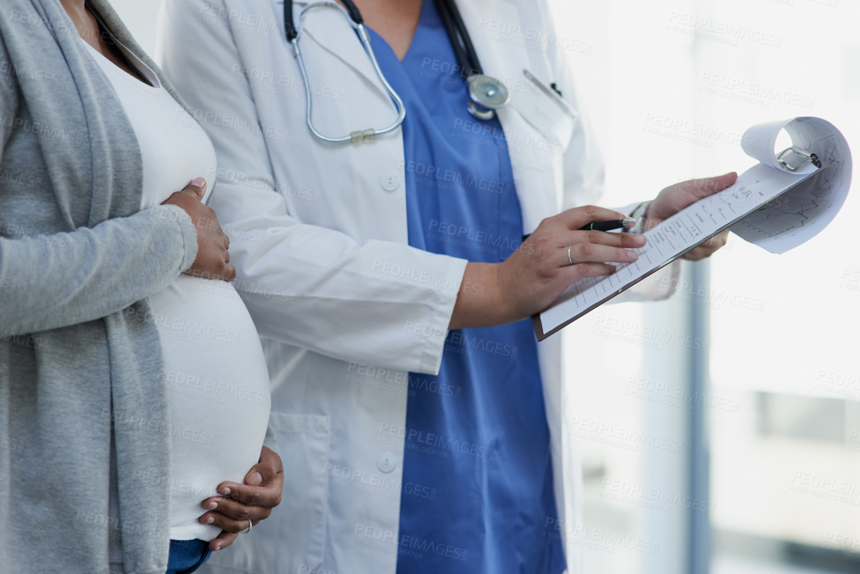 Buy stock photo Shot of an unrecognizable female doctor consulting with a pregnant patient at a hospital during the day