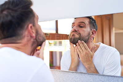 Buy stock photo Shot of a handsome young man going through his morning routine at home