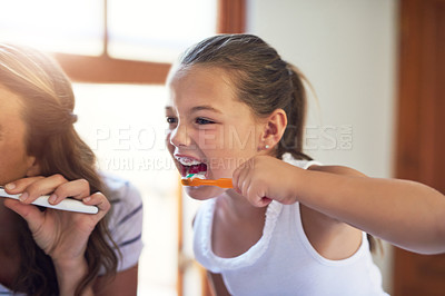 Buy stock photo Shot of an adorable little girl bushing her teeth with her mother at home
