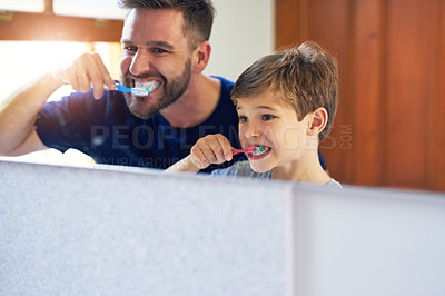 Buy stock photo Shot of a father and his little son brushing their teeth together at home