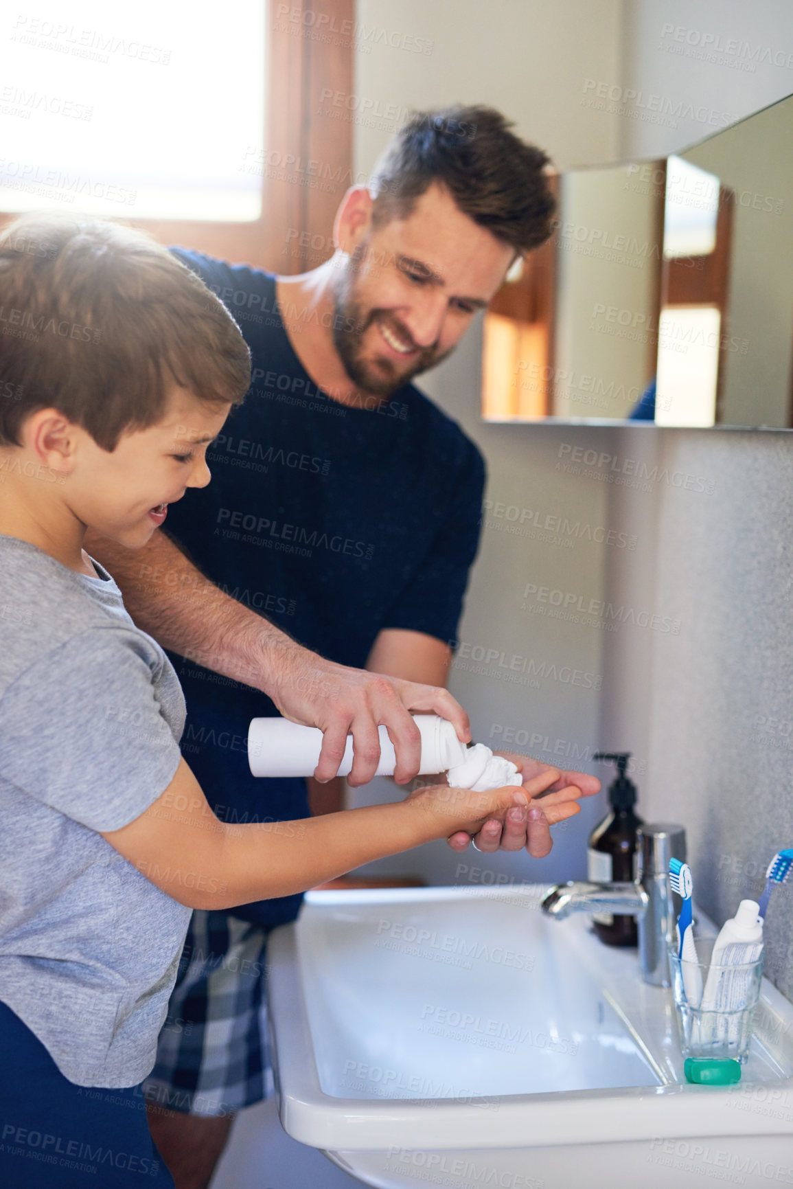 Buy stock photo Shot of a father squeezing shaving cream into his son's hands in the bathroom