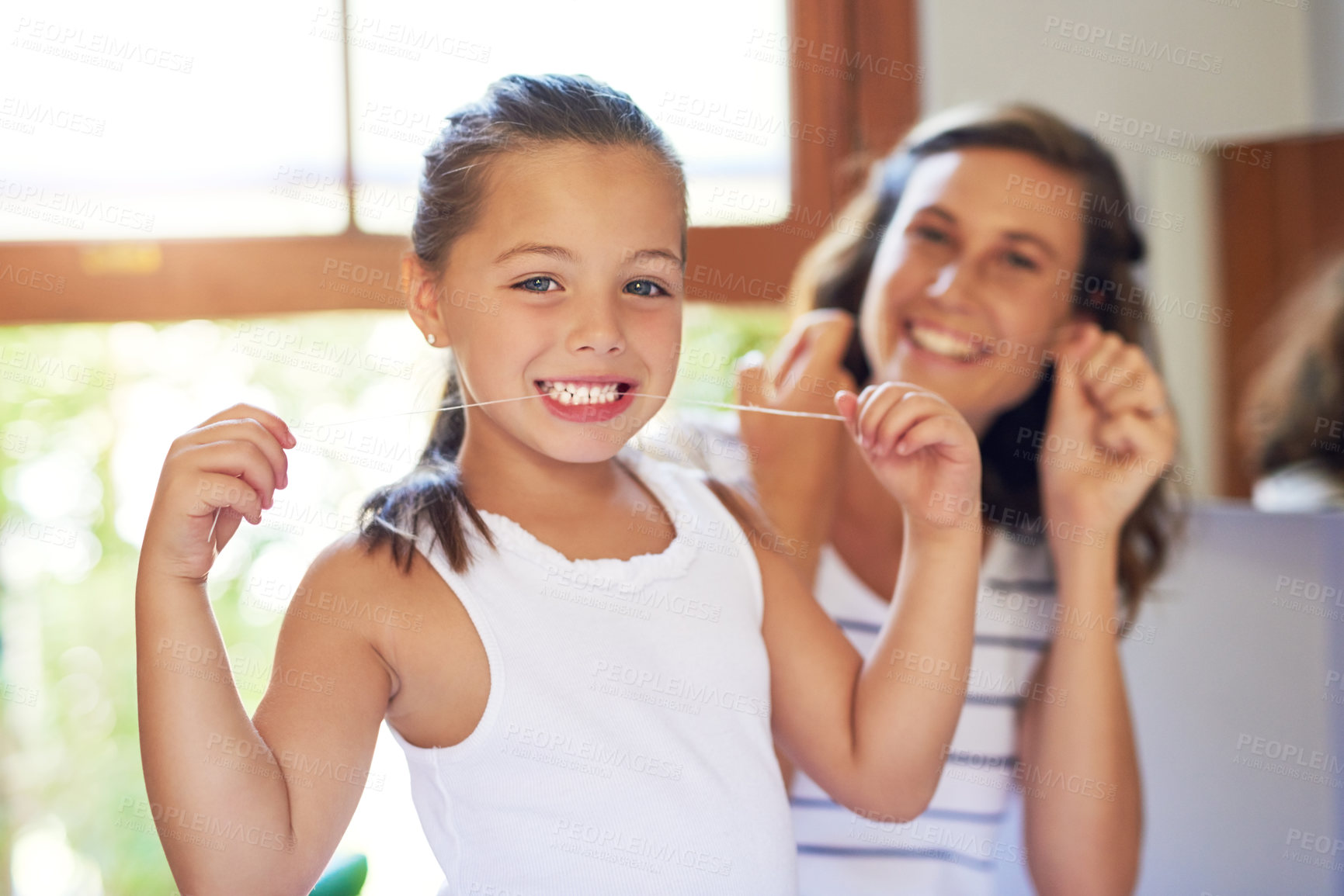 Buy stock photo Portrait of an adorable little girl flossing her teeth with her mother at home