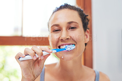 Buy stock photo Portrait of an attractive young woman brushing her teeth at home