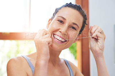 Buy stock photo Portrait of an attractive young woman flossing her teeth at home