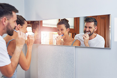 Buy stock photo Shot of a young couple brushing their teeth together at home