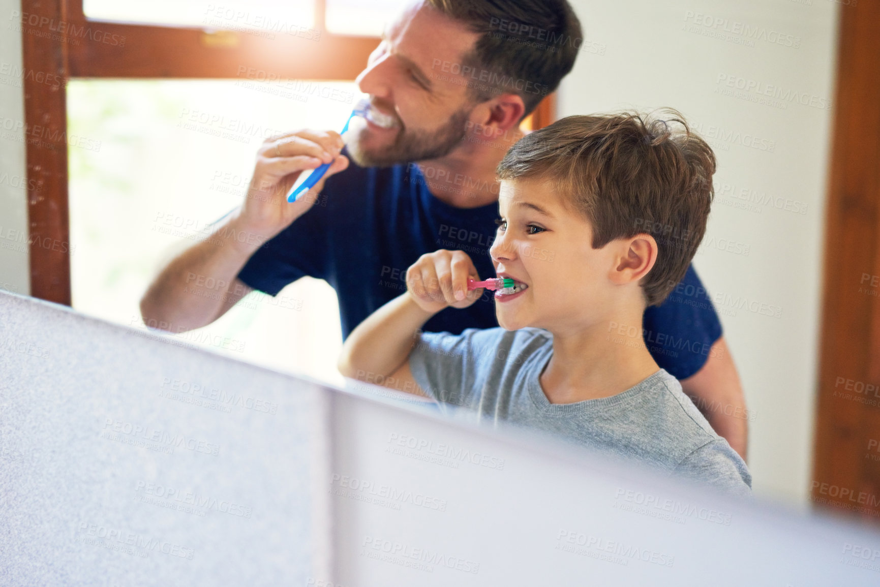 Buy stock photo Shot of a father and his little son brushing their teeth together at home