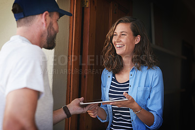 Buy stock photo Shot of a young woman using a digital tablet to sign for her delivery from the courier