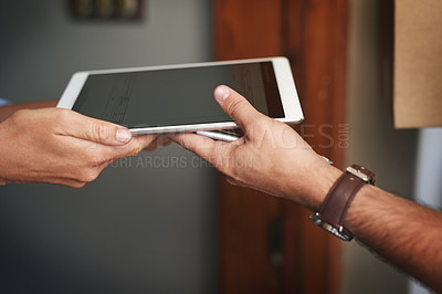 Buy stock photo Closeup shot of an unrecognizable woman using a digital tablet to sign for her delivery from the courier