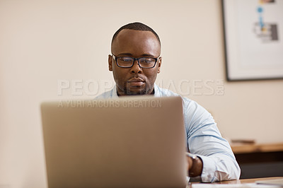 Buy stock photo Cropped shot of a handsome young businessman working on his laptop at home