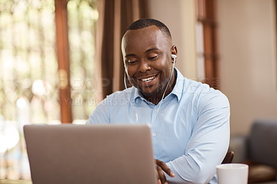 Buy stock photo Cropped shot of a handsome young businessman listening to music while working on his laptop at home