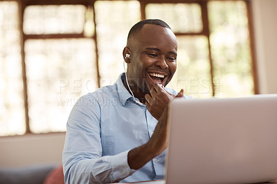 Buy stock photo Cropped shot of a handsome young businessman listening to music while working on his laptop at home