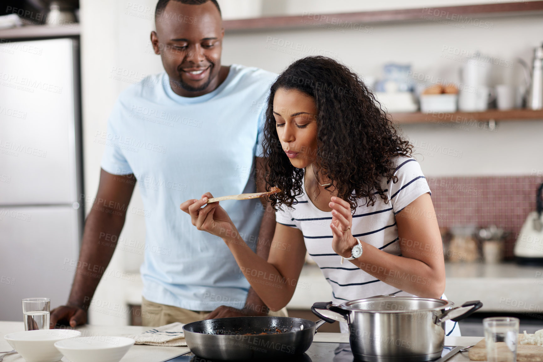 Buy stock photo Cropped shot of a young married couple cooking together in the kitchen at home