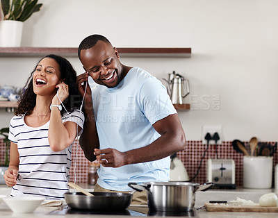 Buy stock photo Cropped shot of a young married couple listening to music while cooking together in the kitchen at home