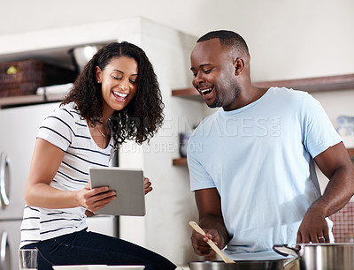 Buy stock photo Cropped shot of a young married couple using a tablet while cooking together in the kitchen at home