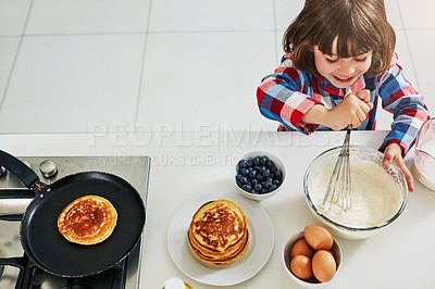 Buy stock photo High angle shot of an adorable little boy making pancakes in the kitchen at home