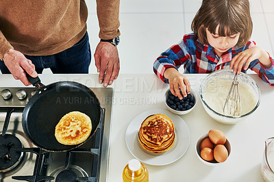 Buy stock photo High angle shot of an adorable little boy making pancakes with his unrecognizable father in the kitchen at home