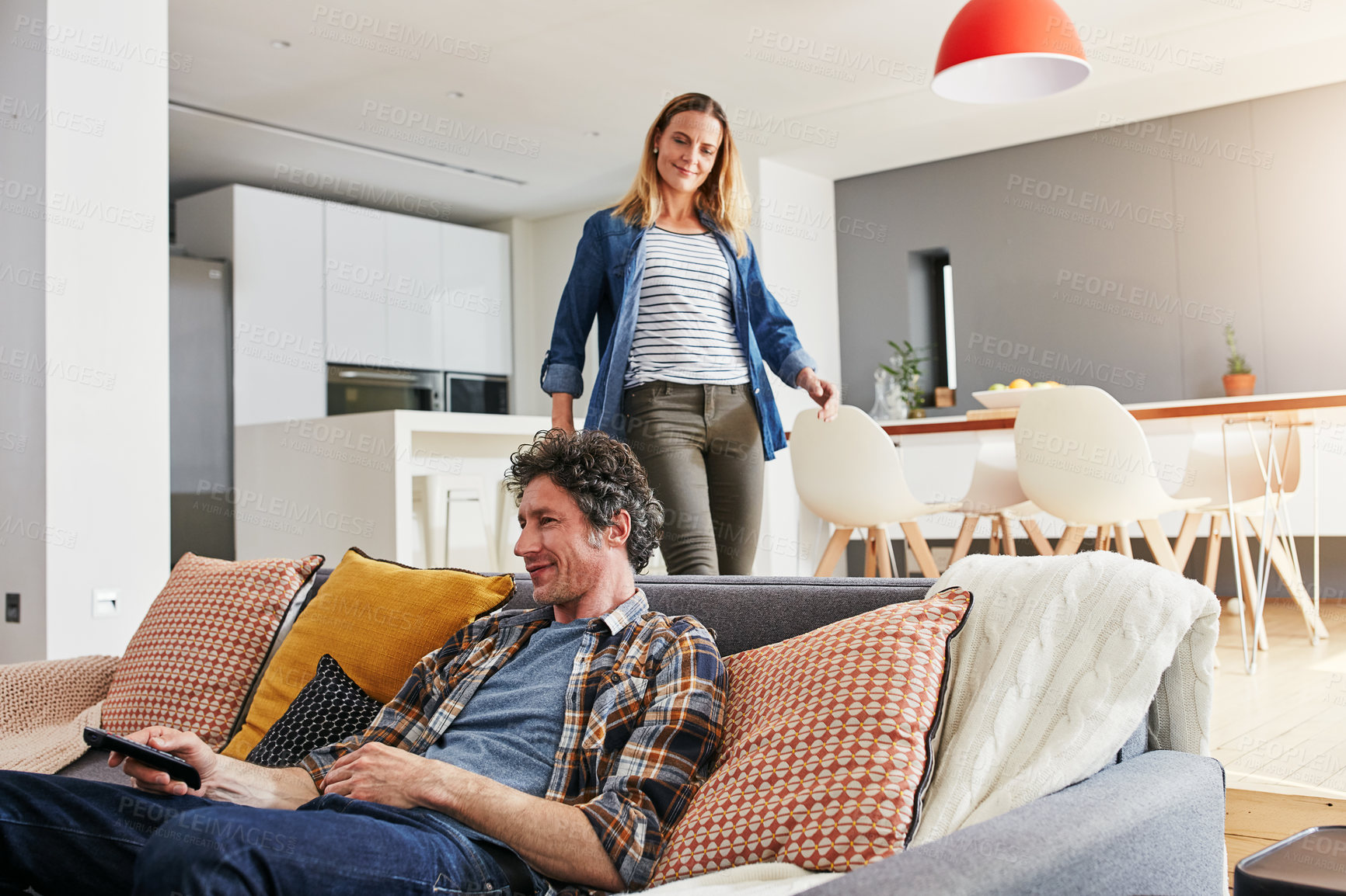 Buy stock photo Cropped shot of a mature man chilling on the sofa while his wife is coming to join him in the living room at home