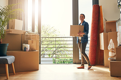 Buy stock photo Portrait of a cheerful middle aged woman holding a box while moving into her new home inside during the day