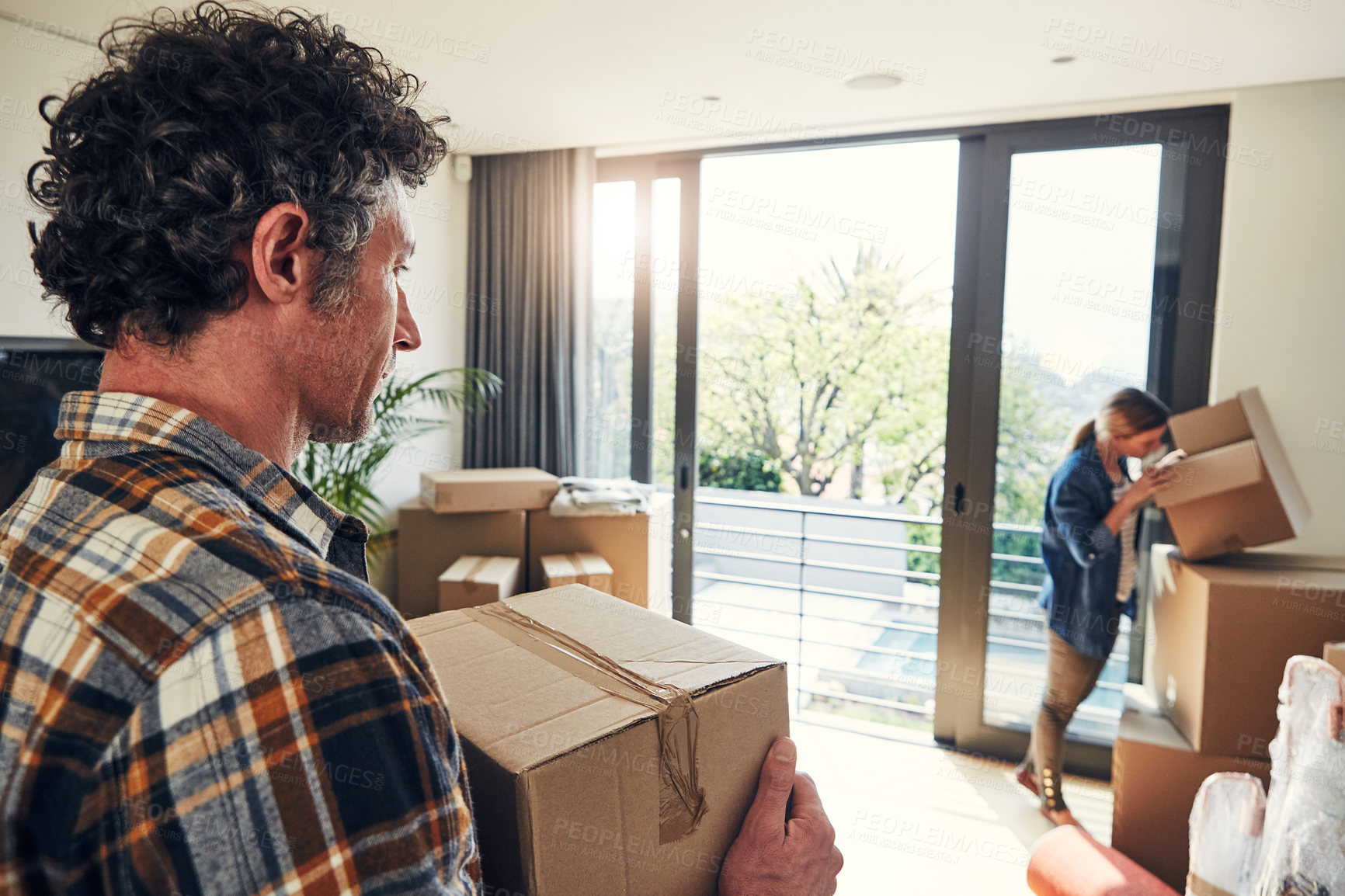 Buy stock photo Shot of a focused middle aged couple packing out a boxes at their new home inside during the day