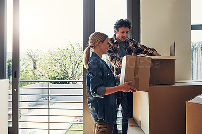 Buy stock photo Shot of a cheerful middle aged couple packing out a boxes at their new home inside during the day