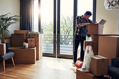 Buy stock photo Shot of a focused middle aged man packing out a box at his new home inside during the day