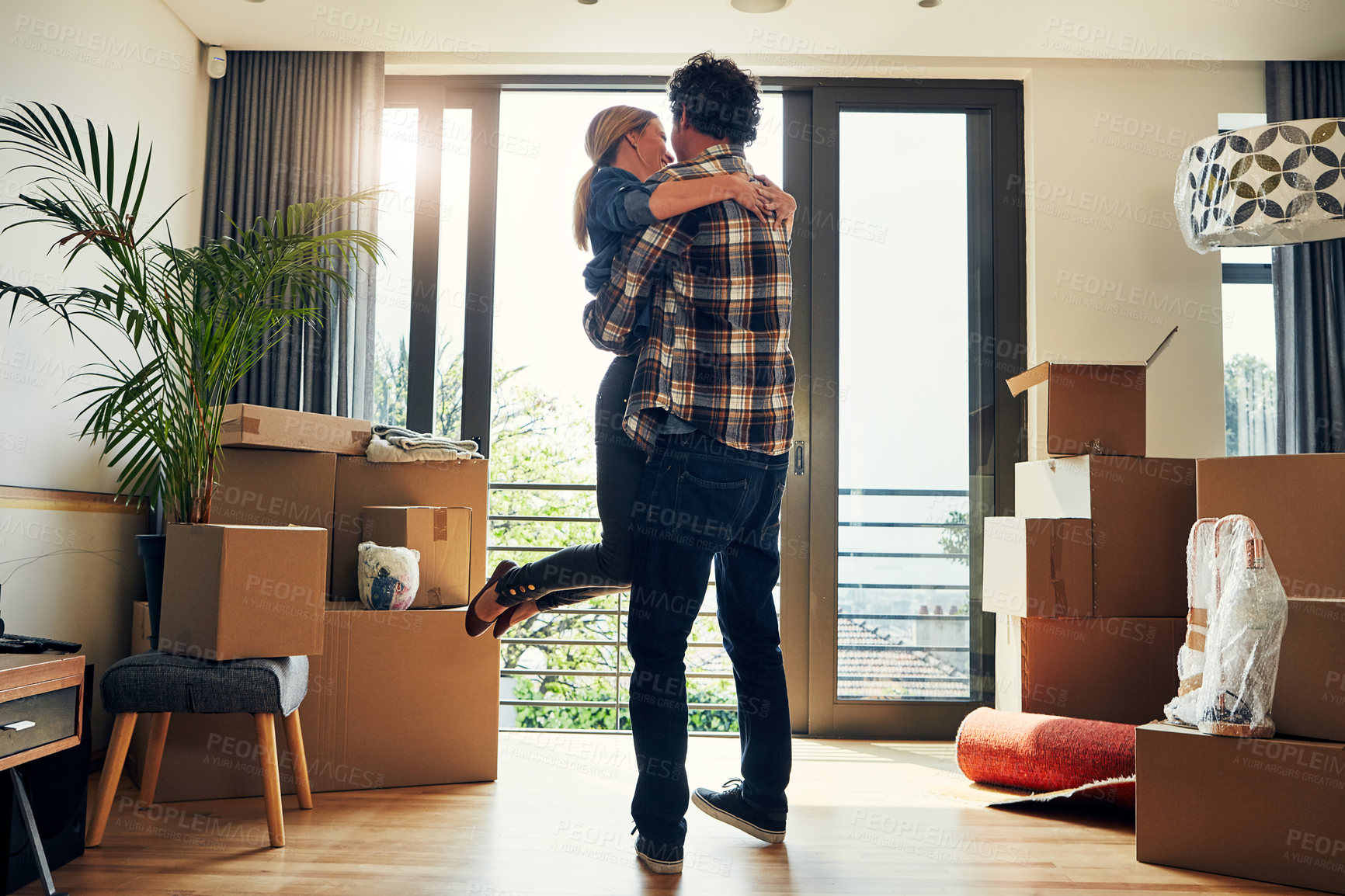 Buy stock photo Shot of a cheerful middle aged couple holding each other in excitement after moving into their new home inside during the day