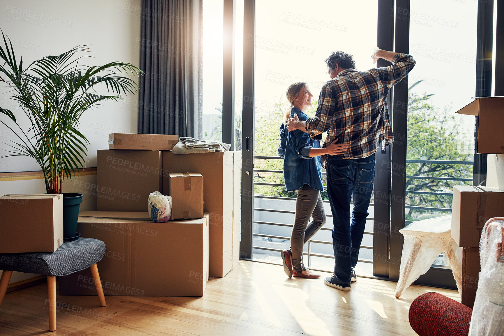 Buy stock photo Shot of a cheerful middle aged couple looking into each other's eyes while being surrounded by boxes on moving day inside at home during the day