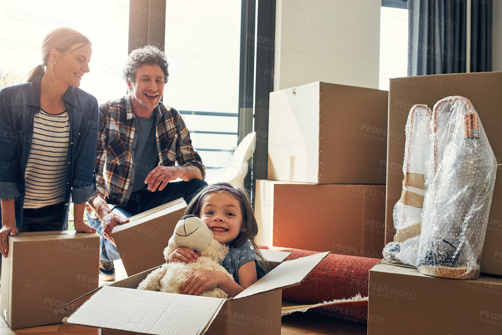 Buy stock photo Portrait of a cheerful loving family packing out boxes together in their new home during the day