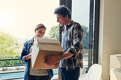 Buy stock photo Shot of a cheerful middle aged couple packing out a boxes at their new home inside during the day