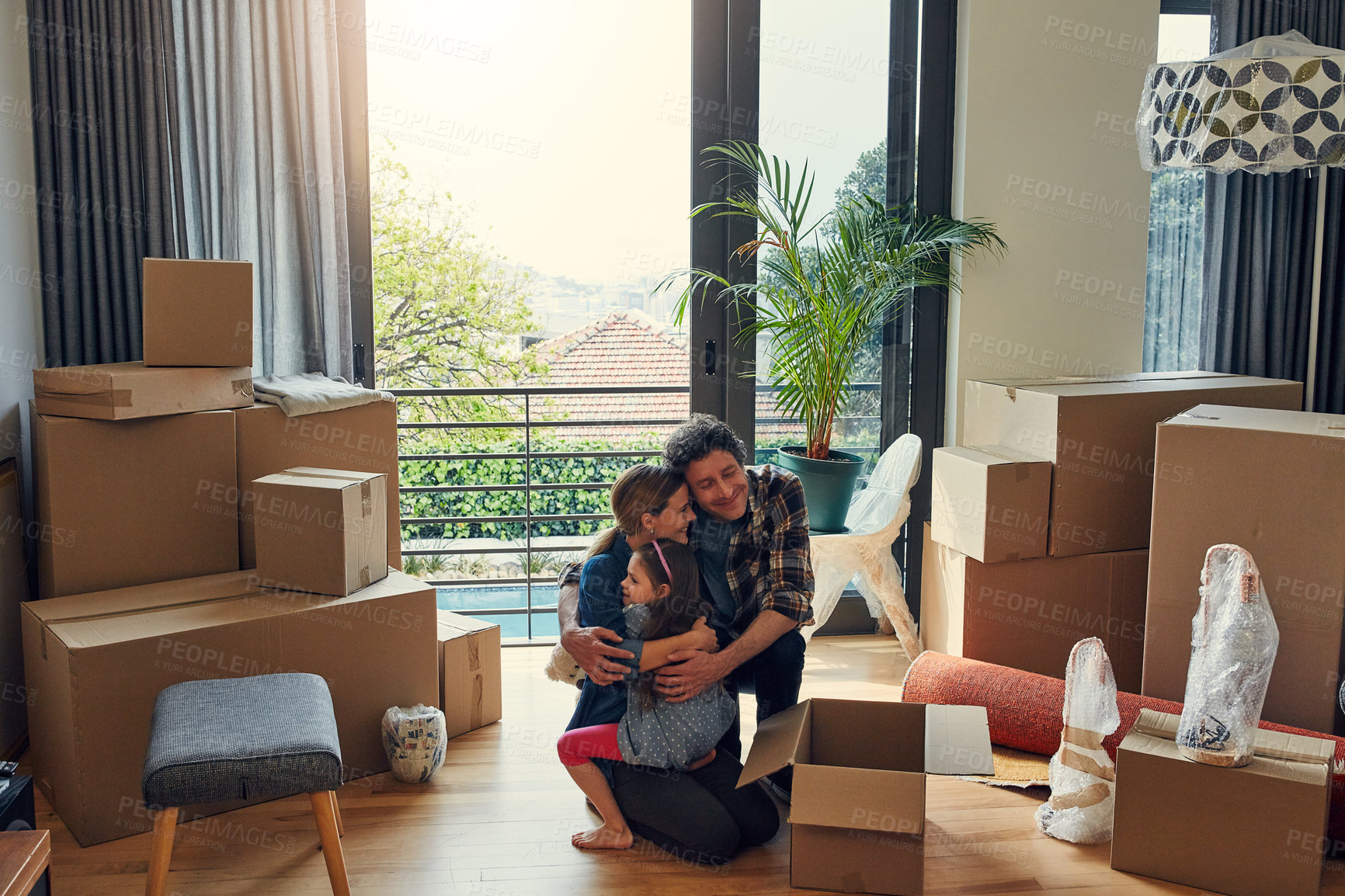Buy stock photo Shot of a cheerful loving family packing out boxes together in their new home while giving each other a big hug during the day