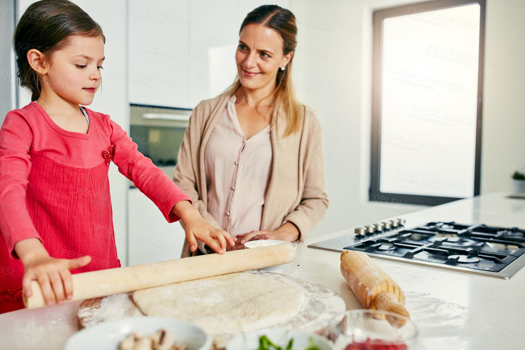 Buy stock photo Shot of a middle aged mother and her daughter preparing a pizza to go into the oven in the kitchen at home
