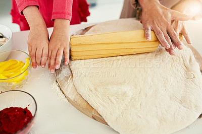 Buy stock photo High angle shot of an unrecognizable mother and her daughter preparing a pizza to go into the oven in the kitchen at home