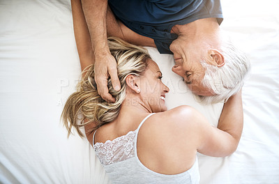 Buy stock photo Shot of an affectionate mature couple lying in bed together at home