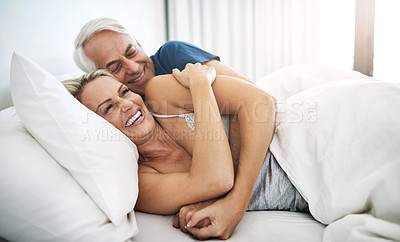 Buy stock photo Shot of an affectionate mature couple lying in bed together at home