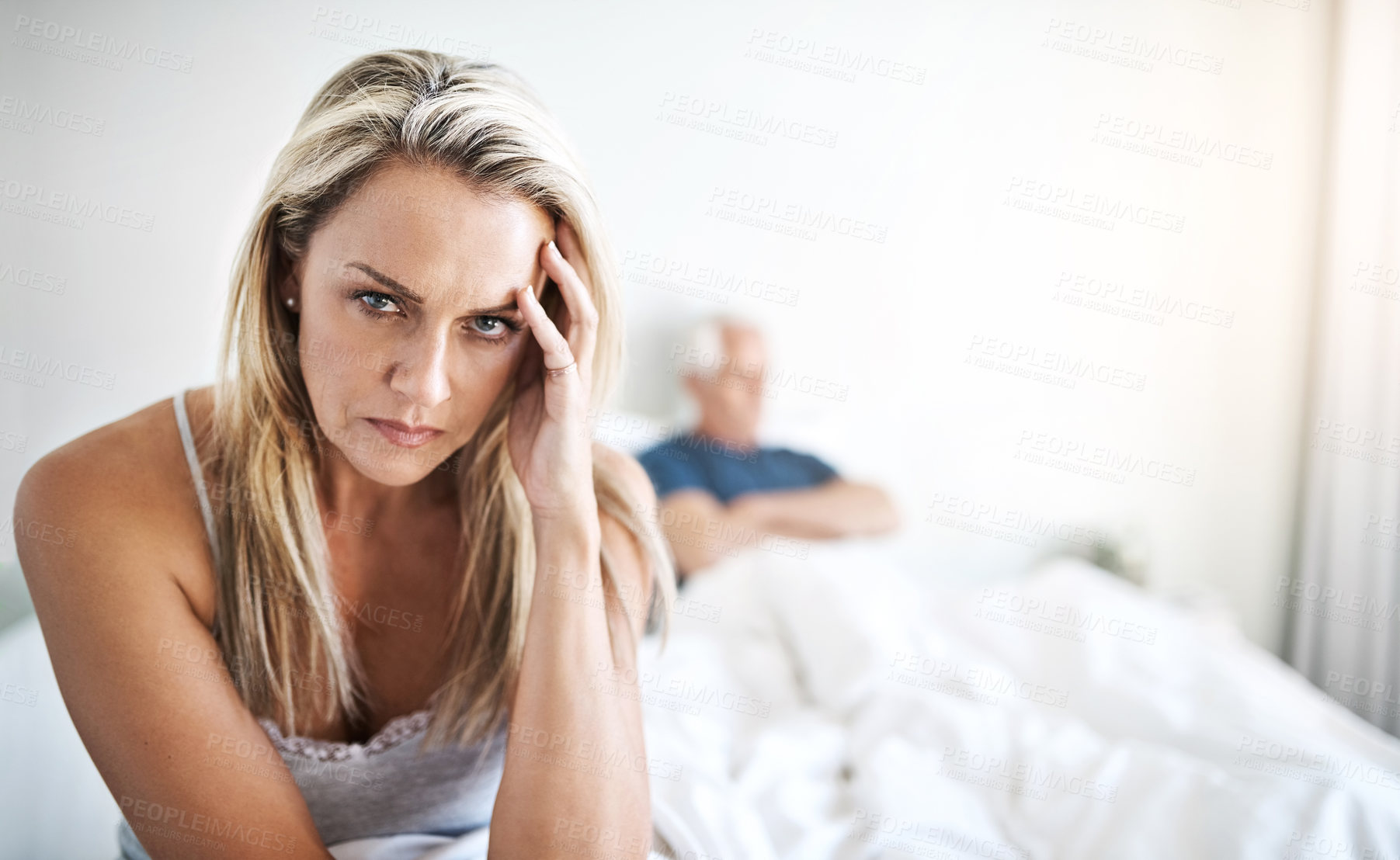 Buy stock photo Portrait of a mature woman looking upset with her husband in the background at home