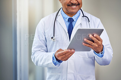 Buy stock photo Shot of an unrecognizable male doctor browsing on a digital tablet inside of a hospital during the day