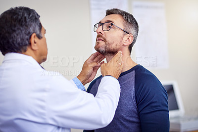 Buy stock photo Shot of a confident mature male doctor doing a checkup on a patient while standing inside of a hospital during the day
