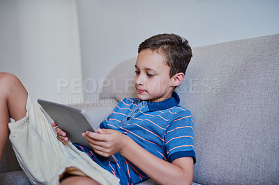Buy stock photo Cropped shot of an adorable little boy using a tablet on the sofa at home