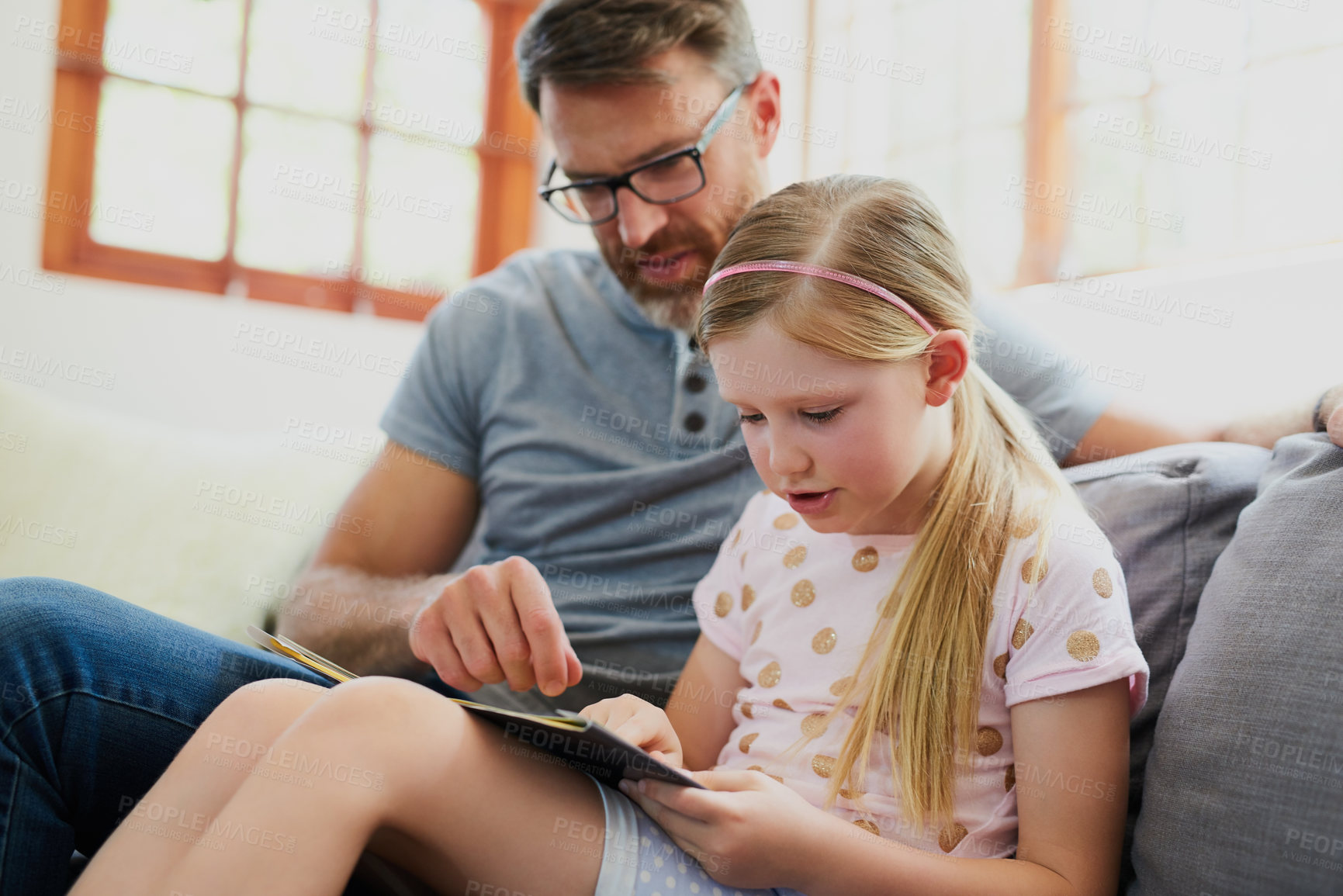 Buy stock photo Cropped shot of a mature father and his adorable daughter reading a book together on the sofa at home