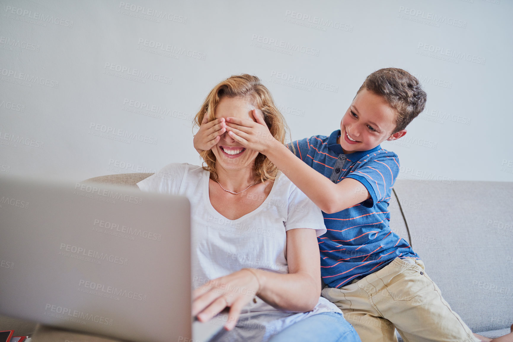 Buy stock photo Cropped shot of a mother using a laptop while her son surprises her and plays peekaboo at home