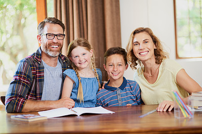 Buy stock photo Cropped shot of two parents helping their adorable children with schoolwork at home