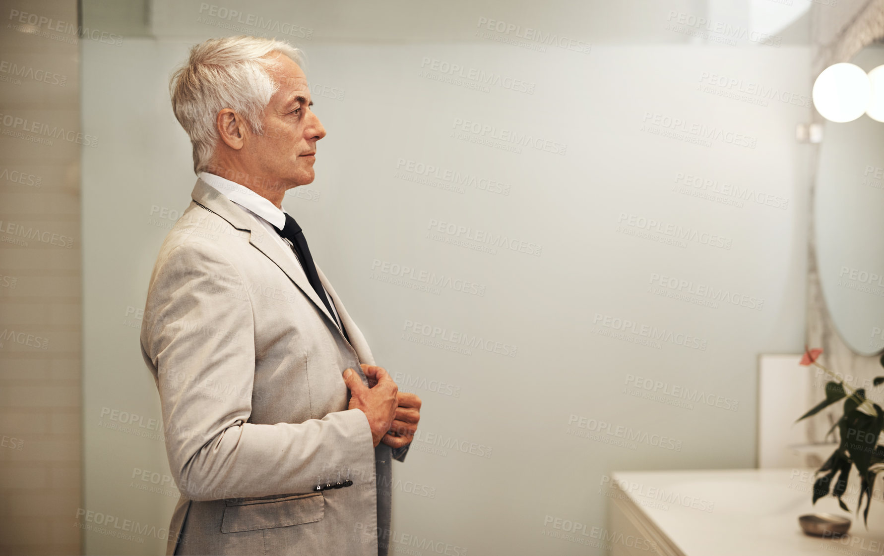 Buy stock photo Shot of an confident mature businessman looking at his reflection in a mirror while getting dressed at home during the day