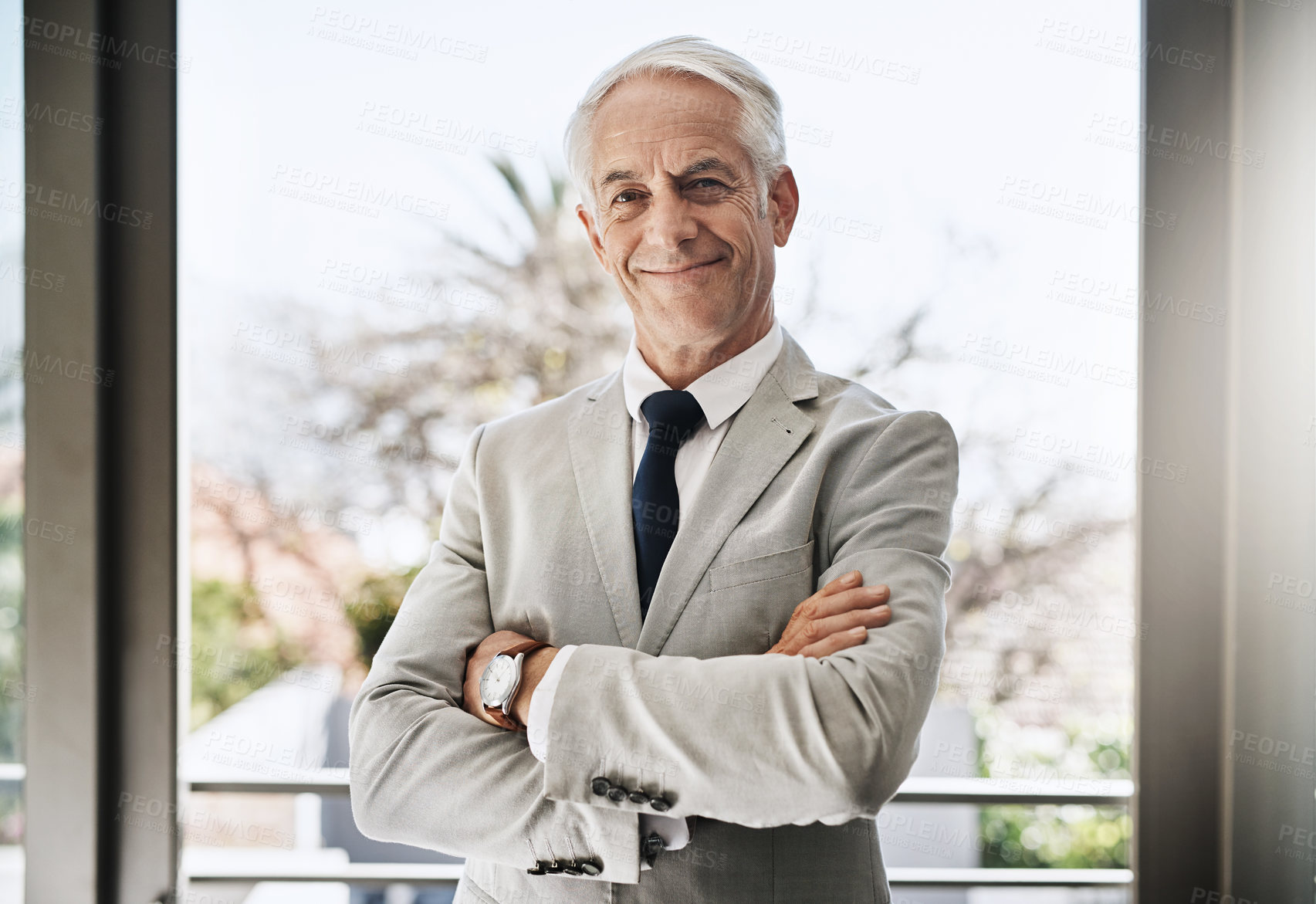 Buy stock photo Portrait of a confident mature businessman wearing a business suit while standing with his arms folded at home during the day