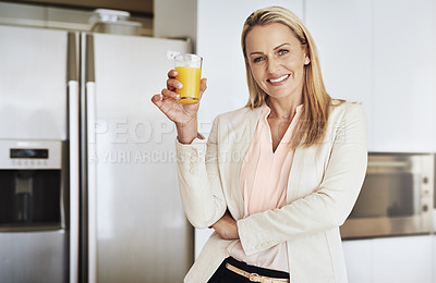 Buy stock photo Portrait of a cheerful middle aged businesswoman enjoying a glass of orange juice in the kitchen during the day