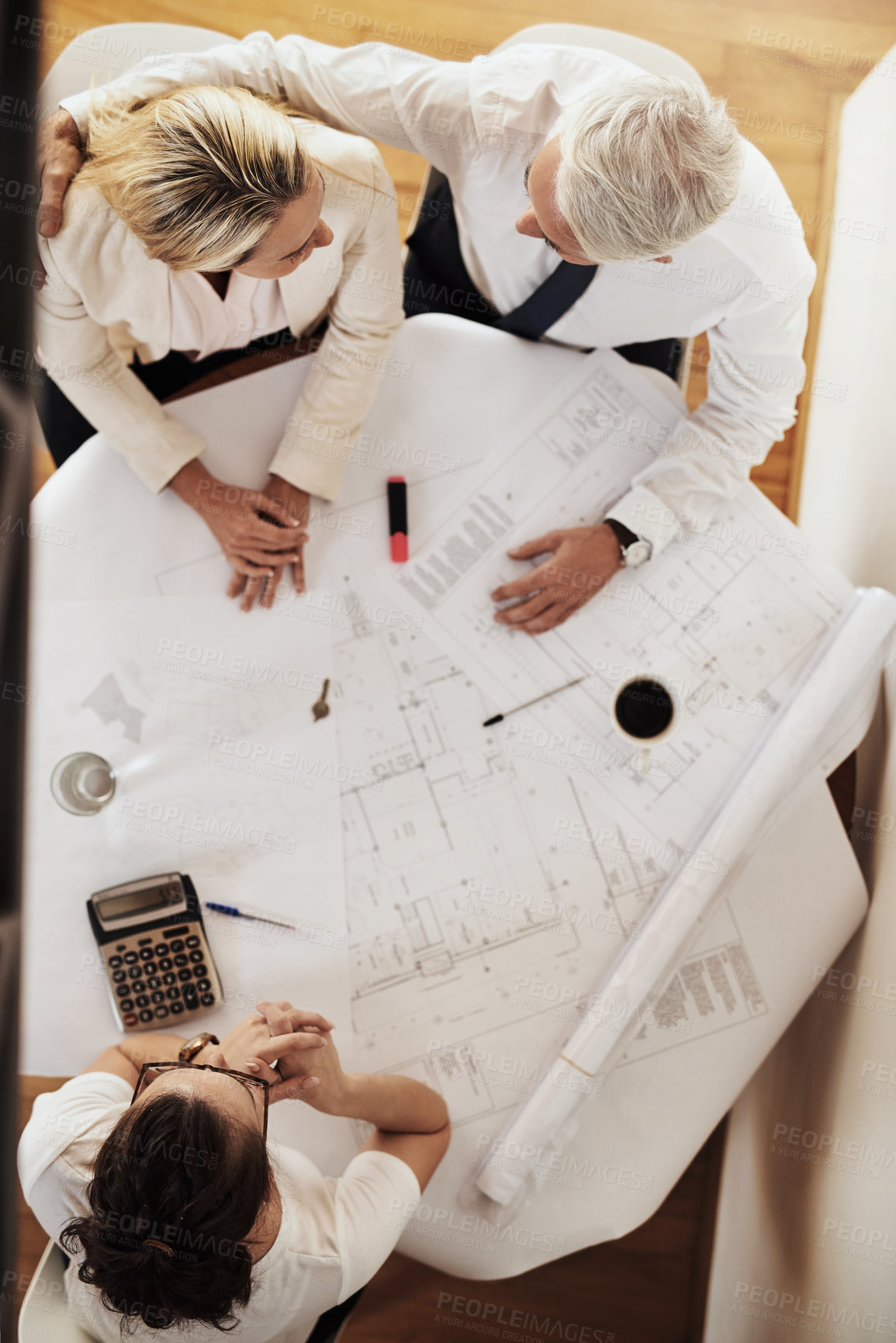 Buy stock photo High angle shot of a cheerful mature couple having a discussion with an architect over blueprints around a table during the day
