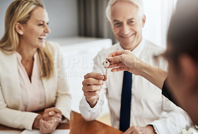 Buy stock photo Shot of a cheerful mature couple receiving keys from a real estate agent to their new house while being seated around a table