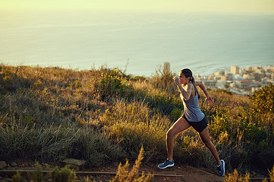 Buy stock photo Shot of a young woman out for a run along a mountain trail