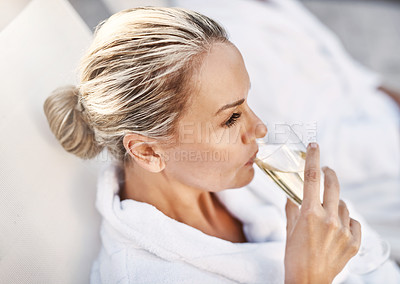 Buy stock photo Shot of a cheerful middle aged woman relaxing on a deckchair while enjoying a glass of champagne outside at a spa during the day
